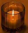 A warm candle glowing in amber glass